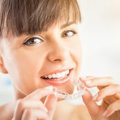 A woman putting in her Invisalign aligners