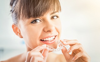 A woman putting in her Invisalign aligners