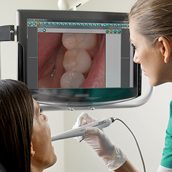 A dentist showing her patient the inside of her mouth by using an intra-oral camera