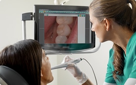 A dentist showing her patient the inside of her mouth by using an intra-oral camera