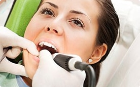 A dentist using a Diagnodent tool to detect cavities in her patient